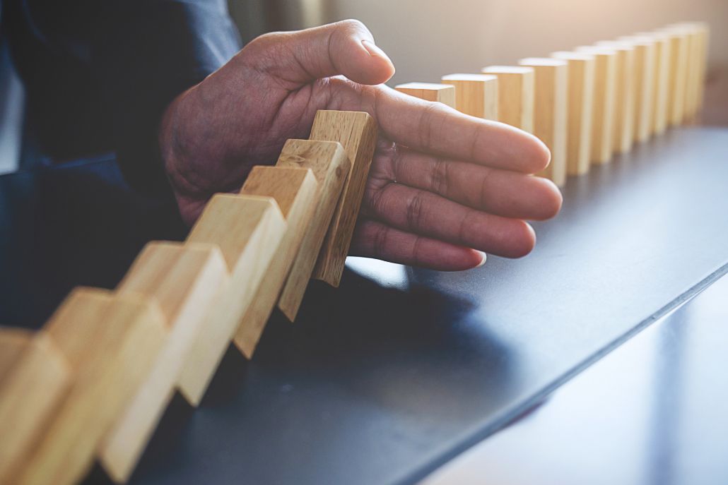 Primo piano su mano che ferma l'effetto domino